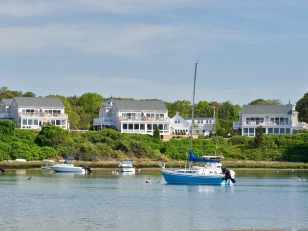 Resort houses on hill with boats on ocean.